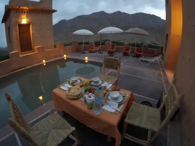 a table with food on it next to a pool at La Kasbah du M'goun in Timit