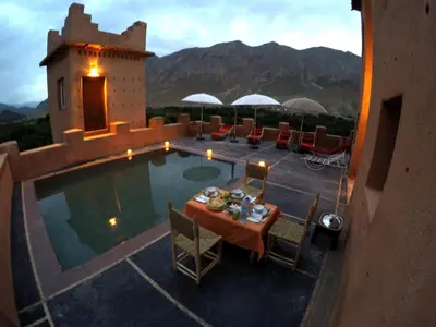 a patio with a table and chairs next to a pool at La Kasbah du M'goun in Timit