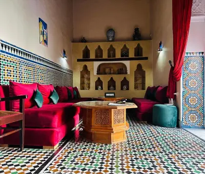 a living room with a red couch and a table at Riad Zitouna in Fès