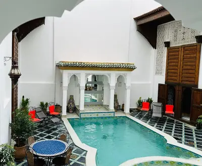 a pool in the middle of a building with red chairs at Riad Zitouna in Fès