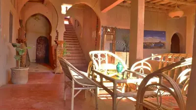 a room with chairs and a table and stairs at Riad Maktoub in Aït Ben Haddou