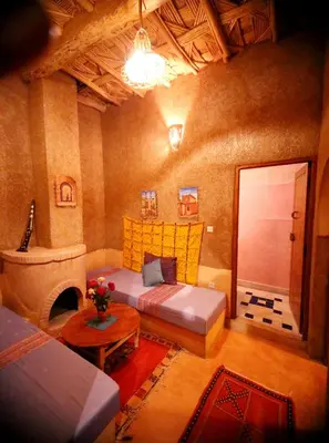 a living room with a bed and a table at Riad Maktoub in Aït Ben Haddou