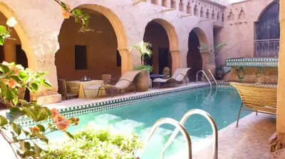 a swimming pool in a courtyard with chairs and tables at Riad Maktoub in Aït Ben Haddou