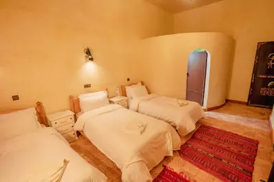 a room with three beds and a red rug at Riad Mamouche in Merzouga