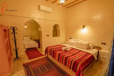 a bedroom with a bed with a red and white blanket at Riad Mamouche in Merzouga