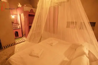 a white bed with a veil on top of it at Riad Mamouche in Merzouga