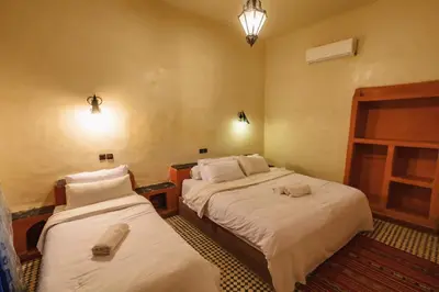 two beds in a hotel room with towels on them at Riad Mamouche in Merzouga