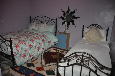 a bedroom with two beds and a clock on the wall at La Colombe Blanche in Moulay Idriss Zerhoun