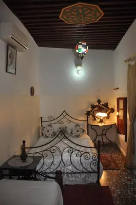 a bedroom with two beds and a chandelier at La Colombe Blanche in Moulay Idriss Zerhoun