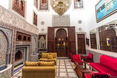 a living room with red chairs and a fireplace at Riad Fes Andalucia in Fès