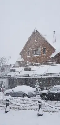 a snow covered yard with cars parked in front of a house at L'empreinte D'ifrane in Ifrane