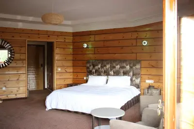 a bedroom with a white bed and wooden walls at L'empreinte D'ifrane in Ifrane