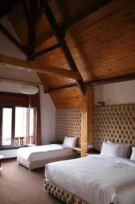 two beds in a room with wooden ceilings at L'empreinte D'ifrane in Ifrane