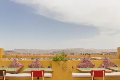 a row of tables and chairs with mountains in the background at Medina social club in Fès