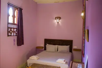 a bedroom with a bed with purple walls and a window at Medina social club in Fès