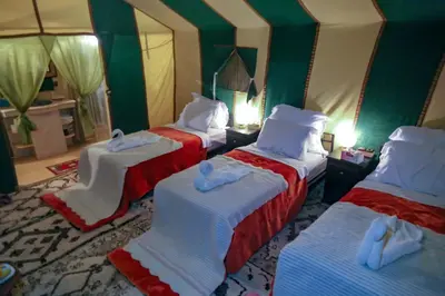 three beds in a room with green walls at Sahara Desert Luxury Camp in Merzouga