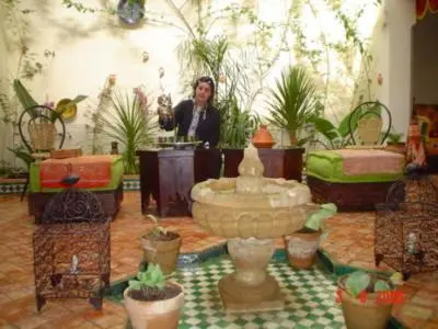 a woman standing in a room with potted plants at Ryad Bahia in Meknès