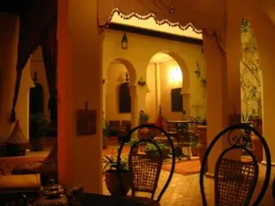 a living room with two chairs and a room with a table at Ryad Bahia in Meknès
