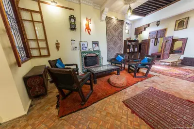 a living room with chairs and a fireplace at Ryad Bahia in Meknès