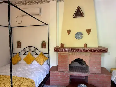 a bedroom with a bed and a brick fireplace at Ryad Bahia in Meknès