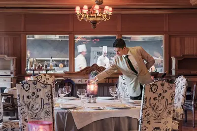 a man is setting a table in a restaurant at Michlifen Resort & Golf in Ifrane