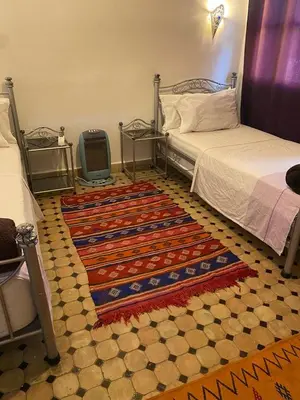 a bedroom with two beds and a rug on the floor at dar hassbia in Fès