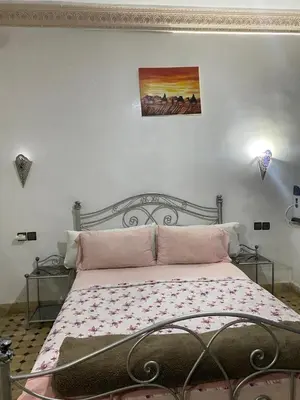 a bedroom with a bed with pink sheets and a painting at dar hassbia in Fès