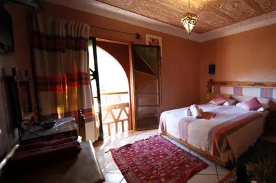 a bedroom with a bed and a large window at Fibule Du Draa Kasbah D'hôtes in Zagora