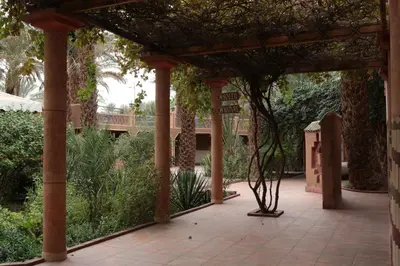 a pergola with a garden in the background at Fibule Du Draa Kasbah D'hôtes in Zagora