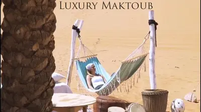 a woman sitting in a hammock on the beach at Luxury Maktoub in Merzouga