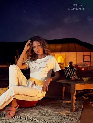 a woman sitting on a table next to a table at Luxury Maktoub in Merzouga