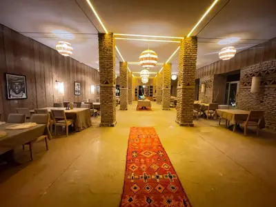 a restaurant with tables and chairs and a red rug at Hotel Kasbah Sahara Services - M'Hamid El Ghizlane in Mhamid