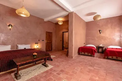 a bedroom with two beds and a table in it at Hotel Kasbah Sahara Services - M'Hamid El Ghizlane in Mhamid