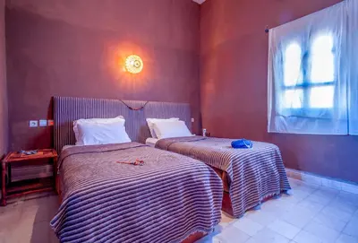 two beds in a room with red walls and a window at Hotel Kasbah Sahara Services - M'Hamid El Ghizlane in Mhamid