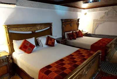 a hotel room with two beds with red pillows at Palais AL Firdaous in Fès