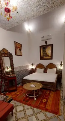 a bedroom with a bed and a table in it at Palais AL Firdaous in Fès