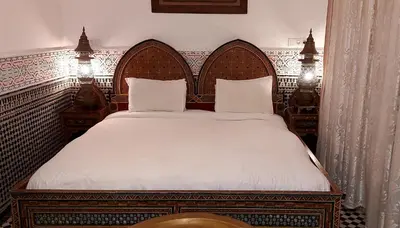 a bedroom with a large bed with white sheets at Palais AL Firdaous in Fès