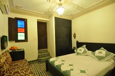 a bedroom with a bed and a window and a chandelier at Riad Salam Fes & Spa in Fès