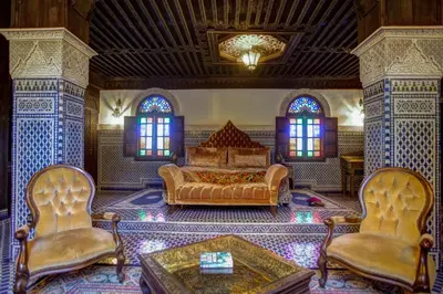 a bedroom with a bed and two chairs and a table at Riad Salam Fes & Spa in Fès