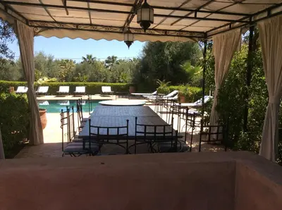 a table and chairs under a pavilion next to a pool at Villa TYCOZ in Marrakech
