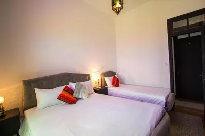 two beds in a room with two lamps on at Hôtel Fontaine Campini in Fès