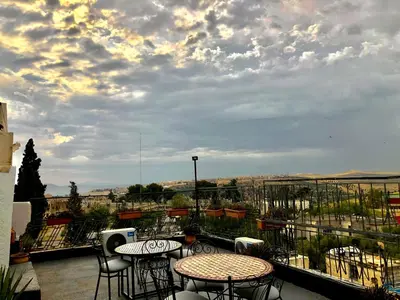a patio with tables and chairs on a balcony at Hôtel Fontaine Campini in Fès