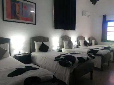 a hotel room with four beds and a window at Hôtel Fontaine Campini in Fès