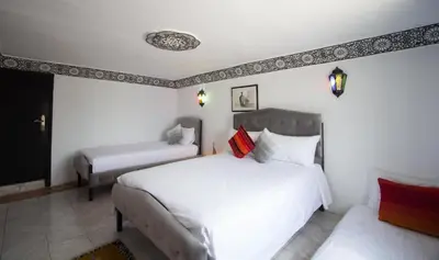 a bedroom with two beds with white sheets and red pillows at Hôtel Fontaine Campini in Fès