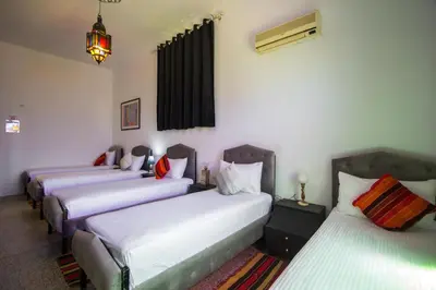 three beds are lined up in a room at Hôtel Fontaine Campini in Fès