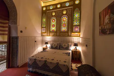 a bedroom with a bed with a stained glass window at Riad Diwan in Fès