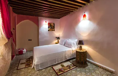 a bedroom with a white bed and two lamps at Riad Diwan in Fès