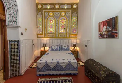a bedroom with a bed and a stained glass window at Riad Diwan in Fès