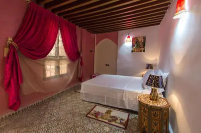 a bedroom with a bed and a window with red curtains at Riad Diwan in Fès