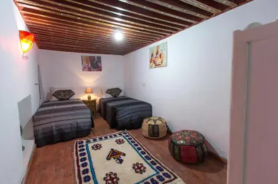 a room with two beds and a table and a rug at Riad Diwan in Fès